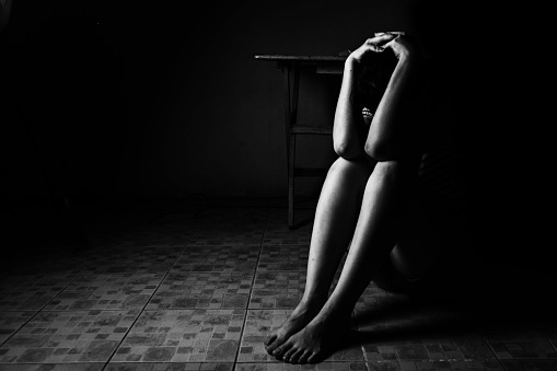A representational image of a girl sitting in the dark