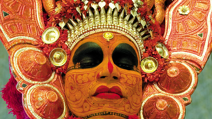 Primary and secondary colours are used to paint the theyyam performer's face and body. (Supplied)