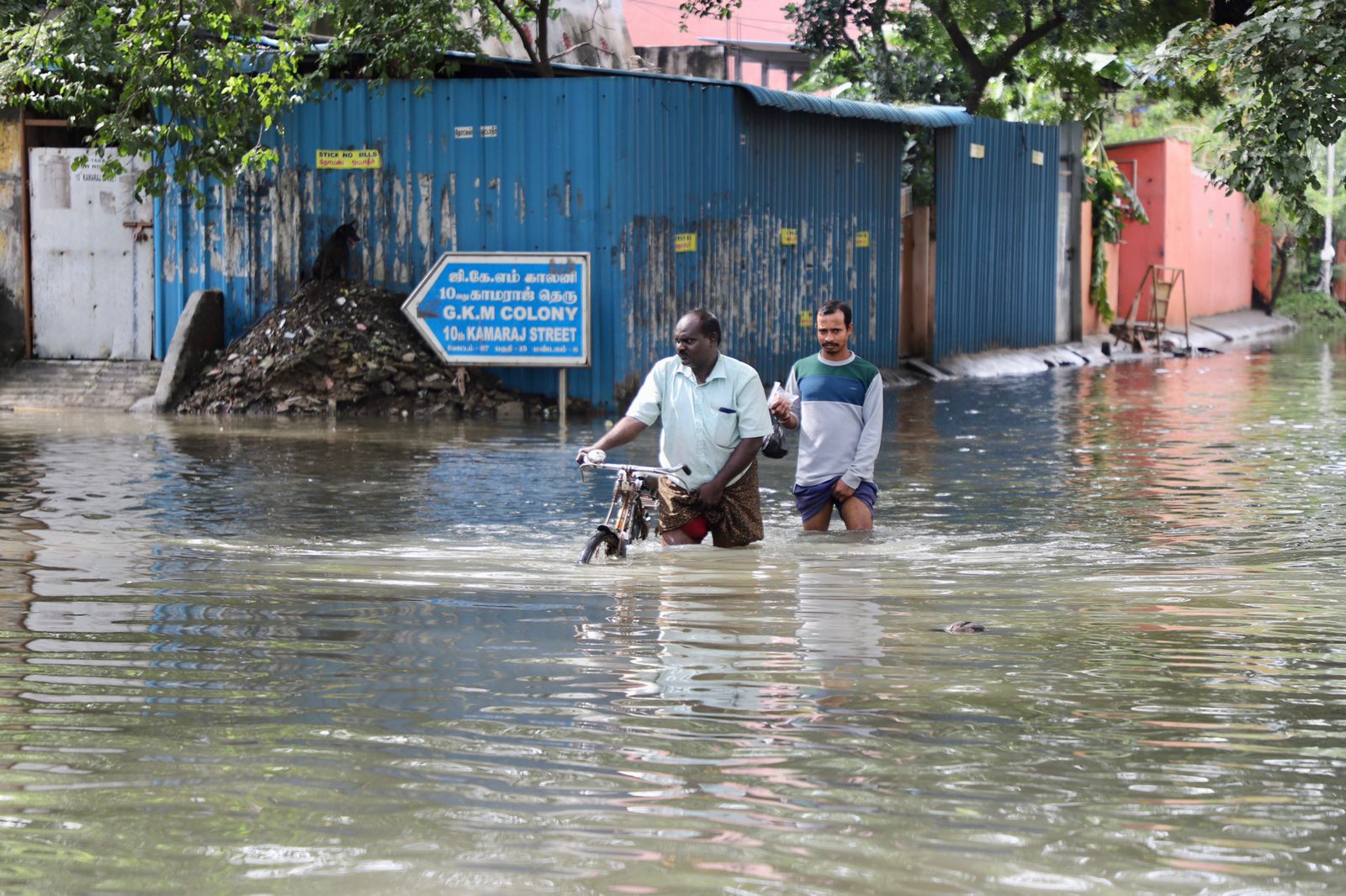 Two people finding their way through the waterlogged road.