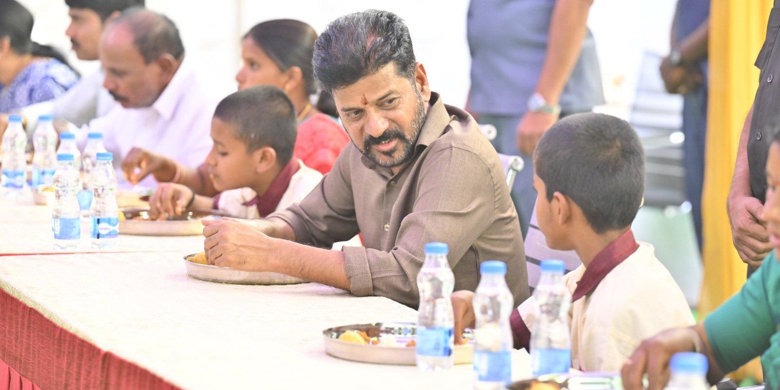 Revanth Reddy having food with school students.