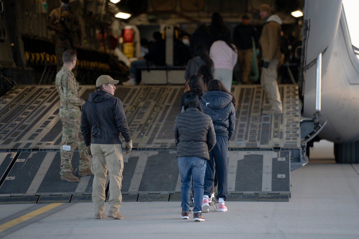 Alleged illegal migrants, handcuffed and chained, board a USAF aircraft. (X/US Air Force)