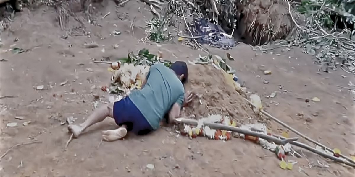 Lakshman lying over his son Bhumik's grave.