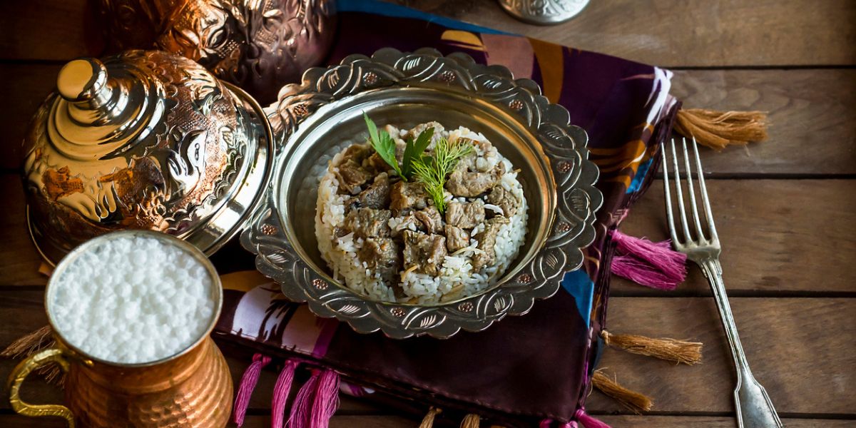 A traditional meal, pilaf and roasted meat, served in silver and copper plates. (iStock)