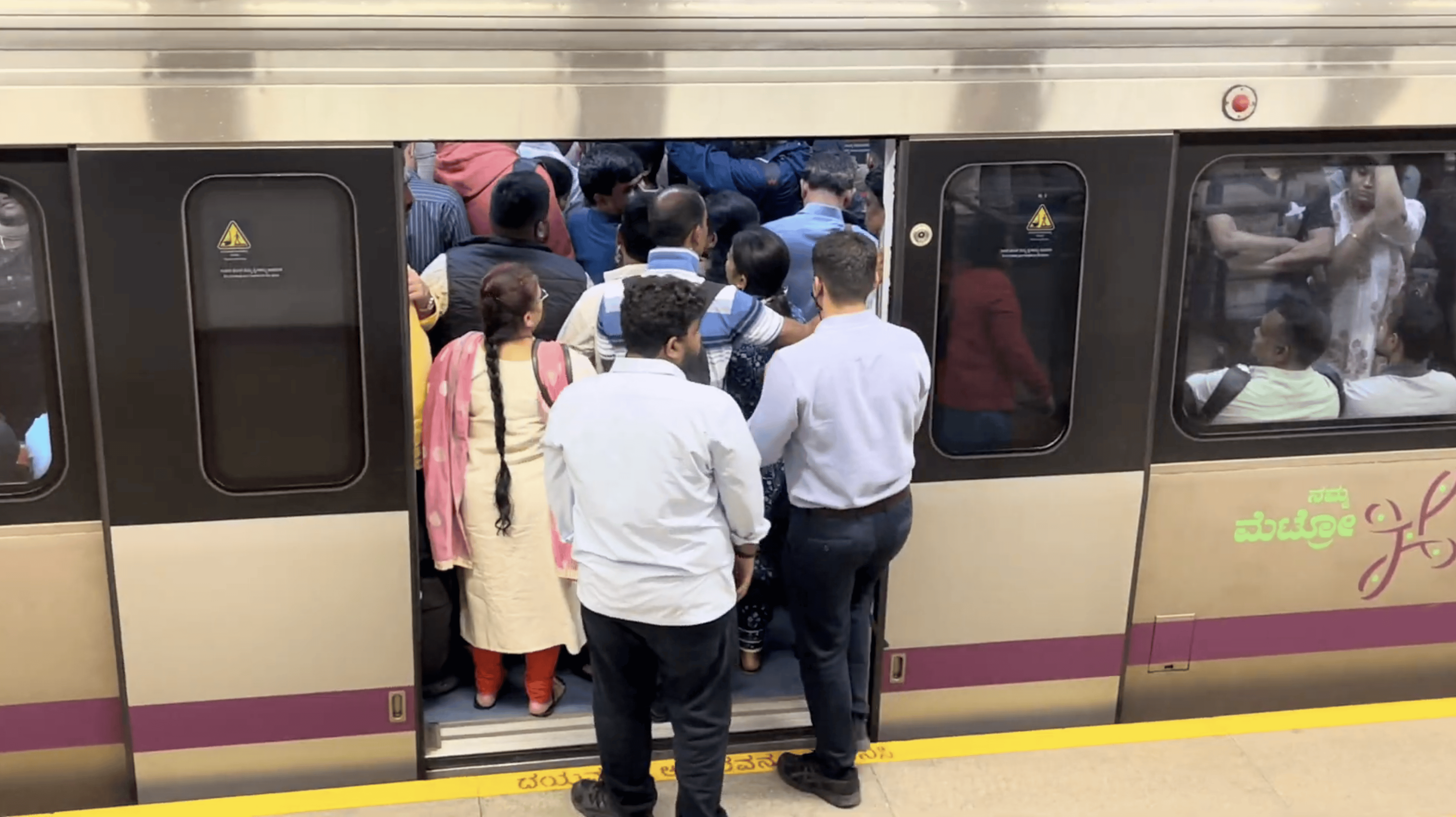 Commuters waiting to enter crowded metro train.