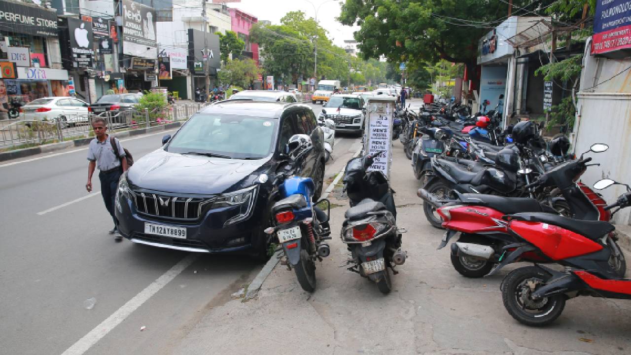 Vehicles parked on the footpath in front of RBL Bank on 4th Avenue Road, Shanthi Colony, Anna Nagar, Chennai, force pedestrians onto the road.
