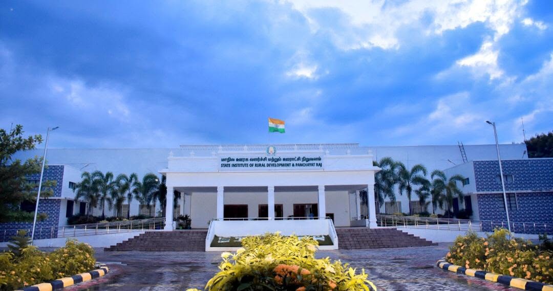 Front view of the State Institute of Rural Development and Panchayat Raj building, with the Indian national flag flying above the entrance.