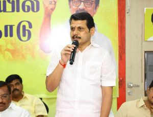 V. Senthil Balaji speaking into a microphone at a public event.